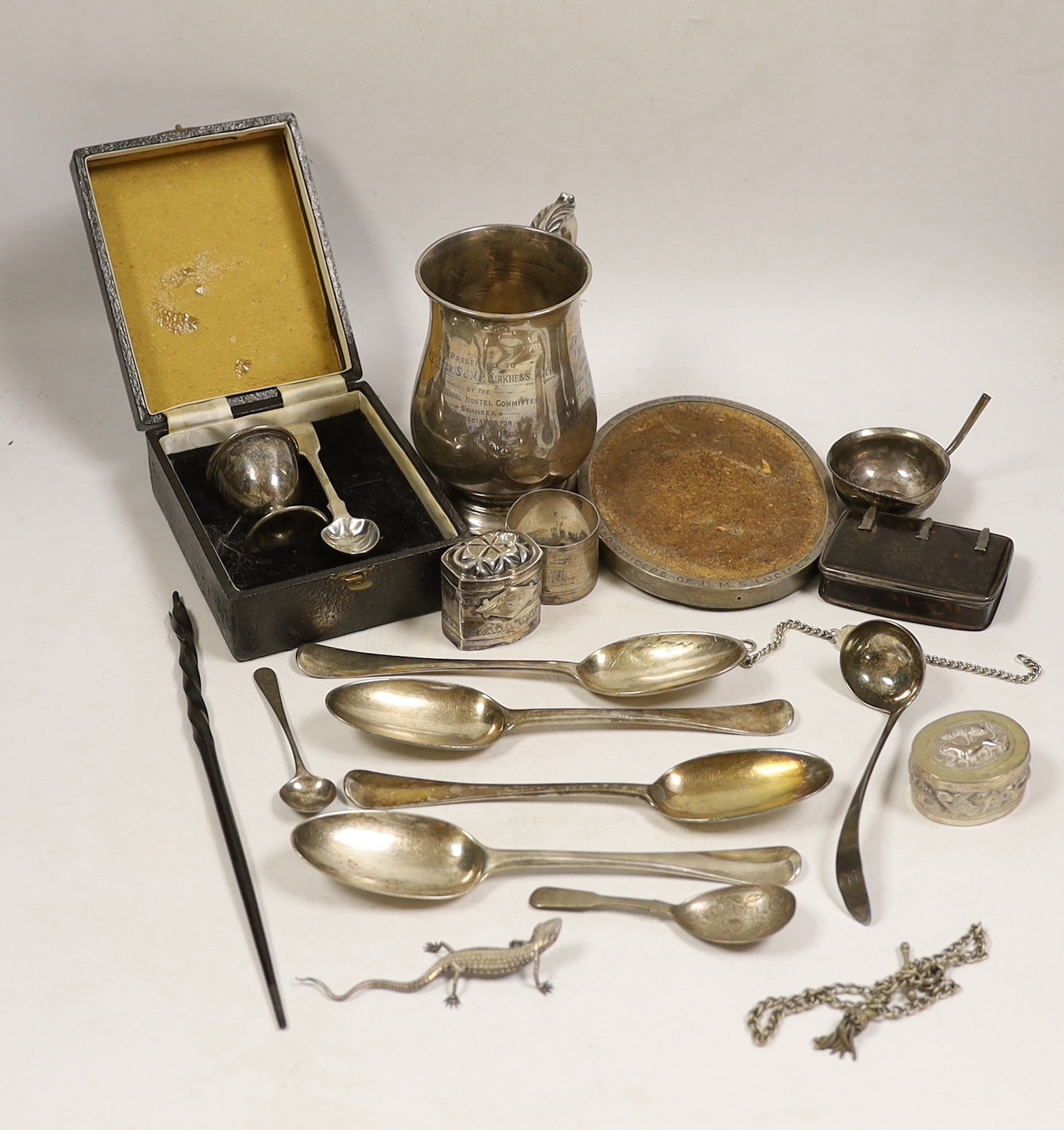 Assorted silver items including a silver mug engraved with signatures and inscription relating to Lieut. Commander S.J.M.P. Kirkness, R.N.R., London, 1942, 13cm, four 18th century base mark table spoons, a George IV cadd